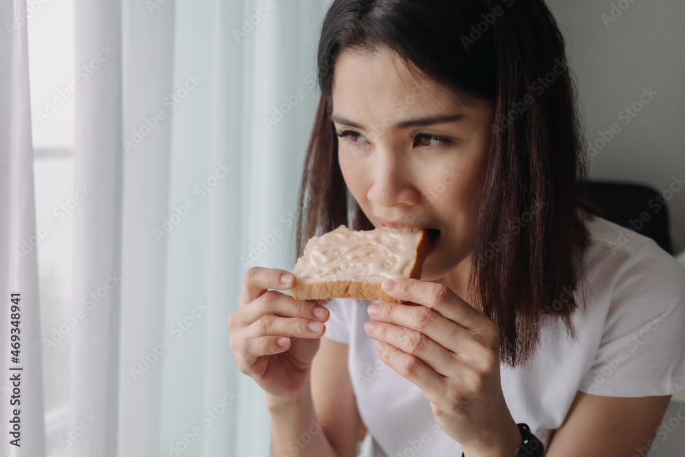 Asian woman eat bread with sweetened condensed milk as easy breakfast. Asian woman eat bread with sweetened condensed milk as easy breakfast.
