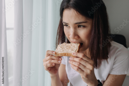 Asian woman eat bread with sweetened condensed milk as easy breakfast.