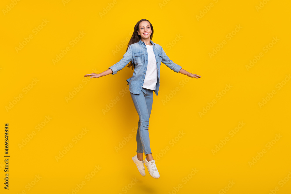 Full size photo of young brown hair funky lady jump wear jeans shirt sneakers isolated on yellow color background
