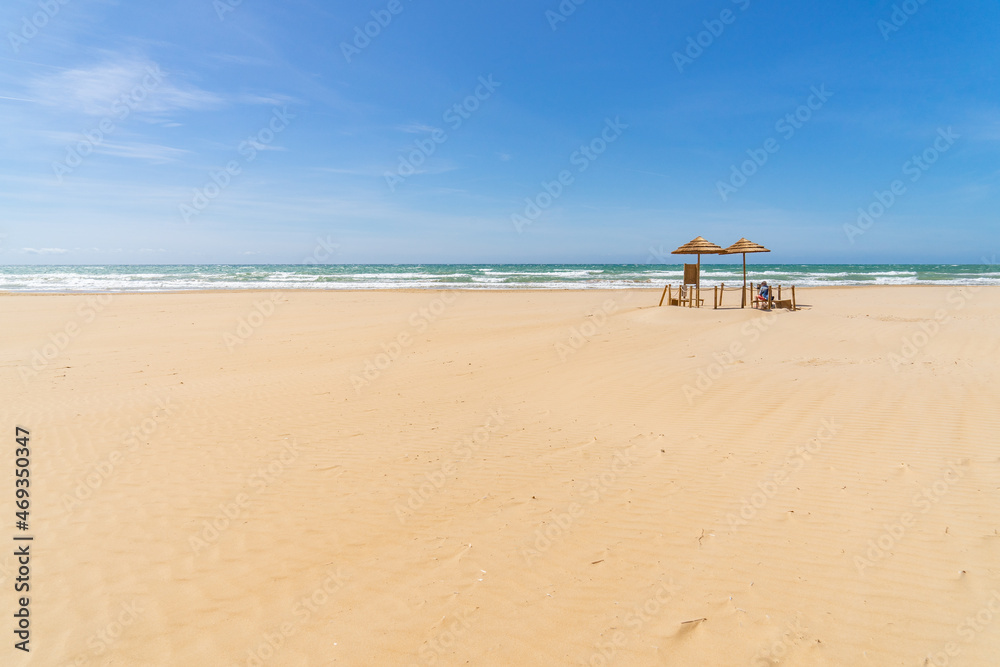 Meer, blauer Himmel und zwei Sonnenschirme auf Sandstrand