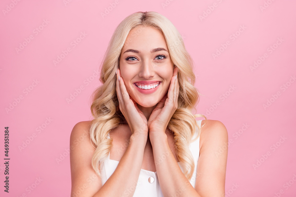 Photo of young attractive girl happy positive smile hands touch cheeks skincare isolated over pink color background Photo of young attractive girl happy positive smile hands touch cheeks skincare isolated over pink color background