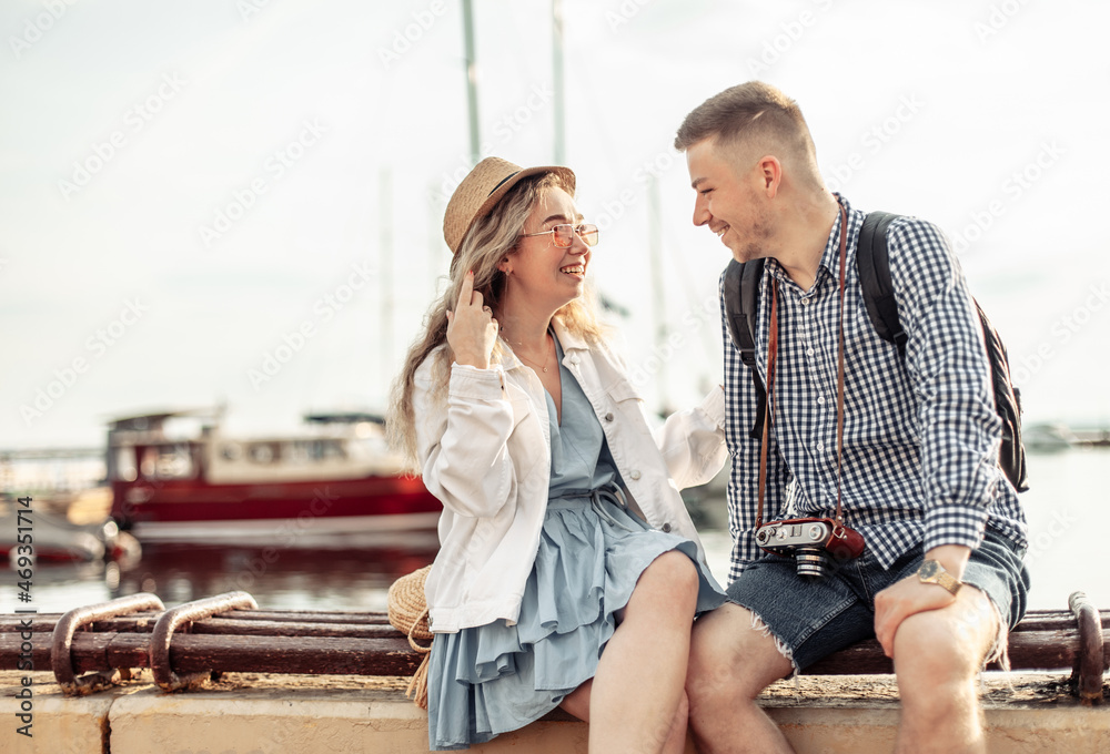 Young loving couple of tourists spend time together on the background of the yacht club