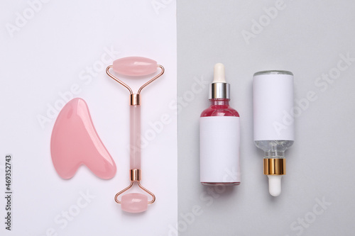 Beautiful composition of mockup serum bottles, pink face roller on gray white background. Creative trendy beauty flat lay