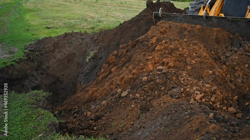 Earthworks in the countryside. Modern bulldozer burying a trench at a construction site. Summer cloudy day