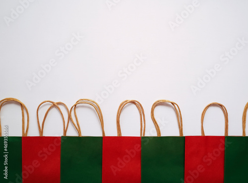 A row of colourful paper shopping bags lying on a white background