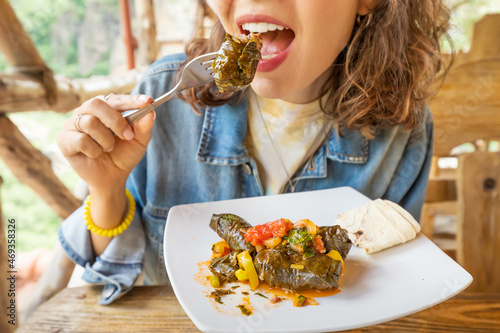 Happy woman eats delicious dolma, a traditional Armenian and Georgian dish made of minced meat wrapped in grape leaves