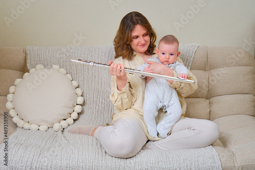 Vászonkép Woman musician with infant baby teaches music and shows the flute