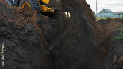 Earthworks in the countryside. Modern bulldozer burying a trench at a construction site. Summer cloudy day