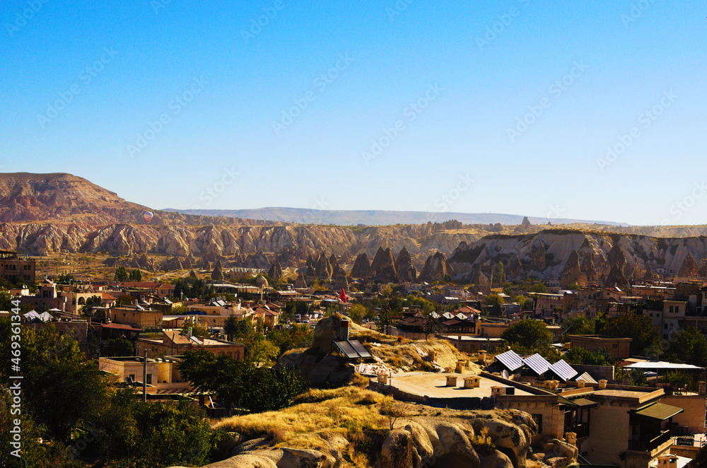 Amazing landscape view of Turkish city Goreme with buildings and cave houses at sunny autumn morning. Fabulous landscapes of the mountains and spectacular rocks formations of Cappadocia