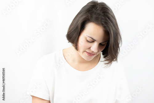 Studio photo of a young sad girl in a white T-shirt on a white background.