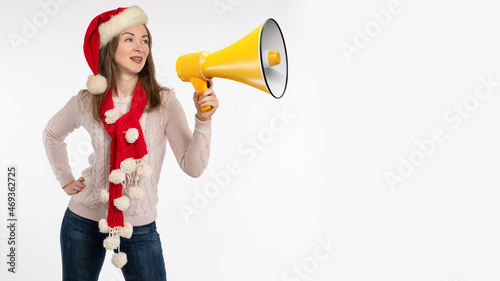 Woman with loudspeaker at christmas time. Girl in santaclaus hat. Christmas shopping advertising concept. Call for Christmas sale. Place for your text. Copy space. Woman with yellow loudspeaker