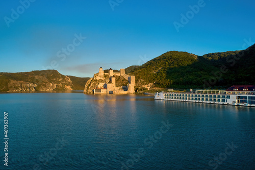 The medieval fortress of Golubac against iron gate of national park Djerdap, mirroring in the waters of the Danube. Colorful sunset light, blue sky. Aerial shot. Famous tourist place, Serbia.