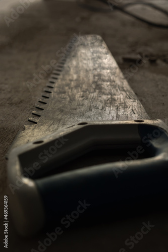 Hand saw for sawing foam block. Close-up, selective focus. Photo in dark key. Room renovation concept.