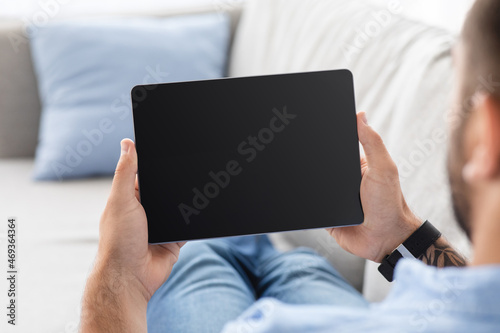 Cropped mature guy on couch, relax and look at tablet with empty screen, watch blog, video and online ad