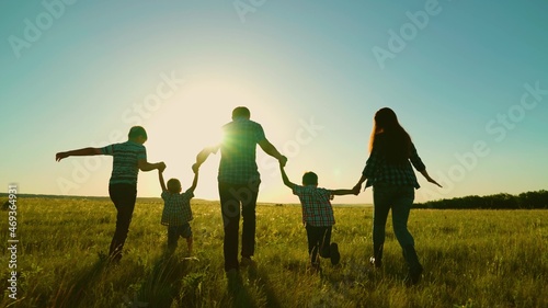 Happy family, parents, children run in the park. The concept of a big happy family. Family walk, silhouette of parents and children at sunset. Mom dad, sons walk together. Family vacation, dreams