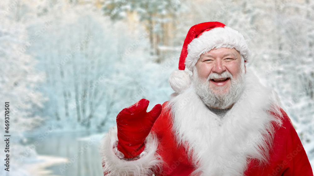 A happy, smiling Santa Claus isolated on a blurred frozen forest. A happy, smiling Santa Claus isolated on a blurred frozen forest.