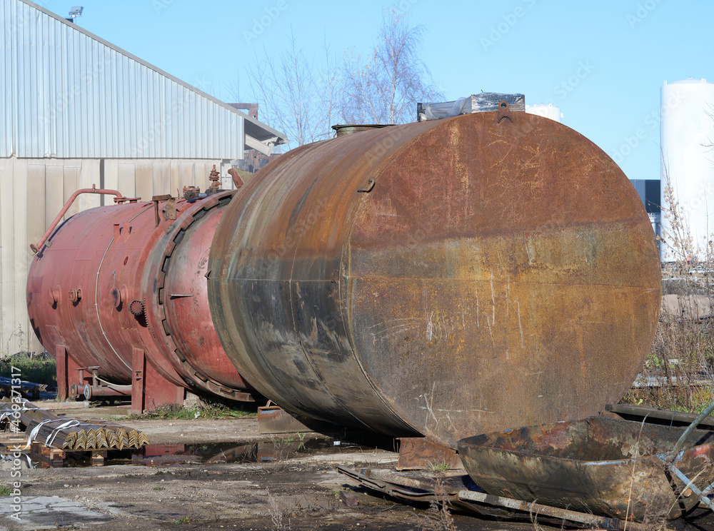 An old abandoned rusty barrel lies in the open air. Second red behind it. High quality photo An old abandoned rusty barrel lies in the open air. Second red behind it. High quality photo