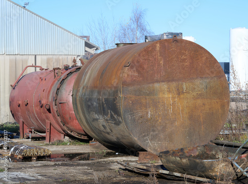 An old abandoned rusty barrel lies in the open air. Second red behind it. High quality photo