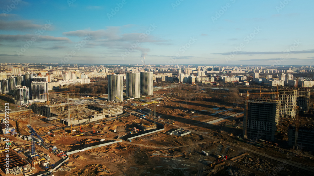 Construction site. Construction of modern multi-storey buildings. The work of construction cranes is visible. Against the background of the blue sky. Aerial photography.