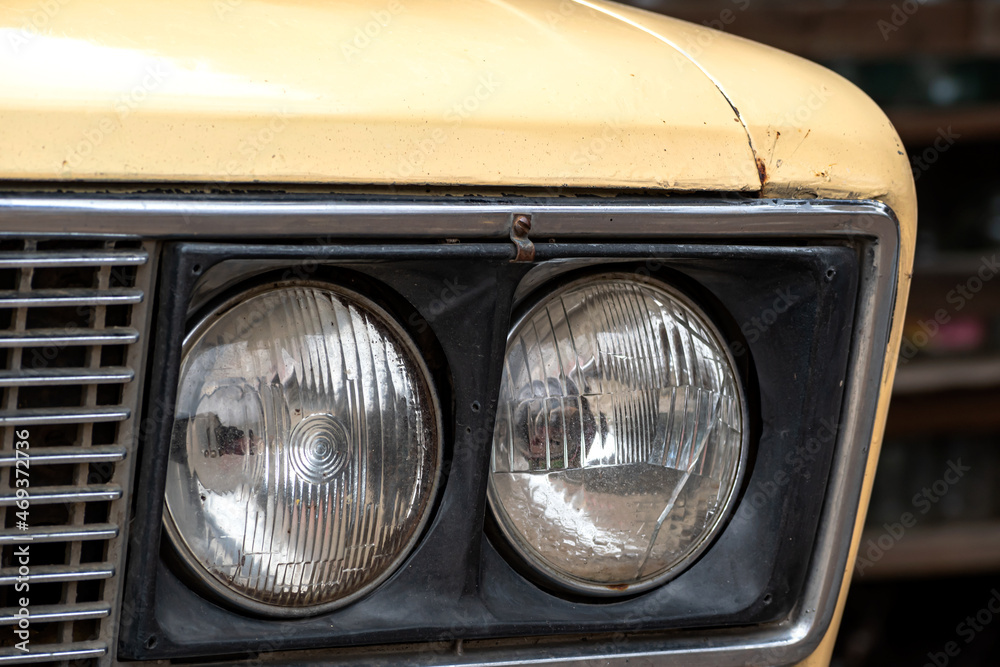 Headlights of an old yellow car.