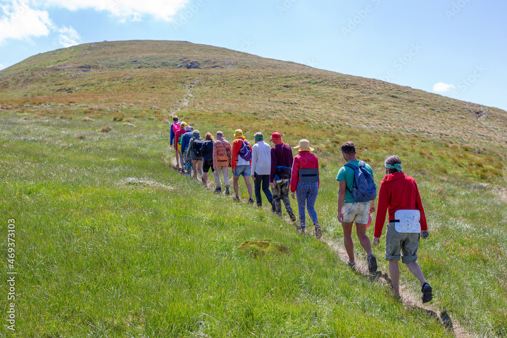 a large group of people goes hiking, walks in the mountains