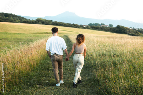 Lovely heterosexual couple in a grass field walking and kissing