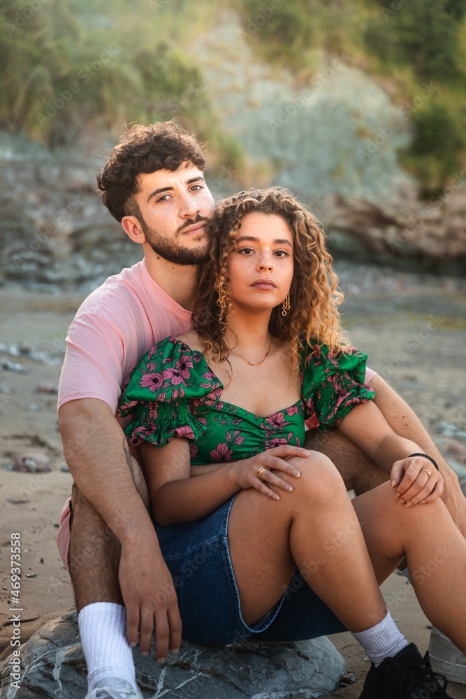 Lovely heterosexual couple on a rocky beach embracing and kissing at the Basque Country.