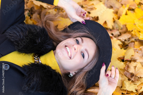 beautiful girl white toothed smile  young happy woman whitened teeth in black hat lying in orange leaves in autumn park. closeup portrait of stylish smiling lady in yellow clothes. fashion female fall