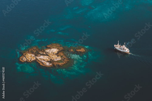 Island in blue sea and ship sailing aerial view drone scenery from above minimal style