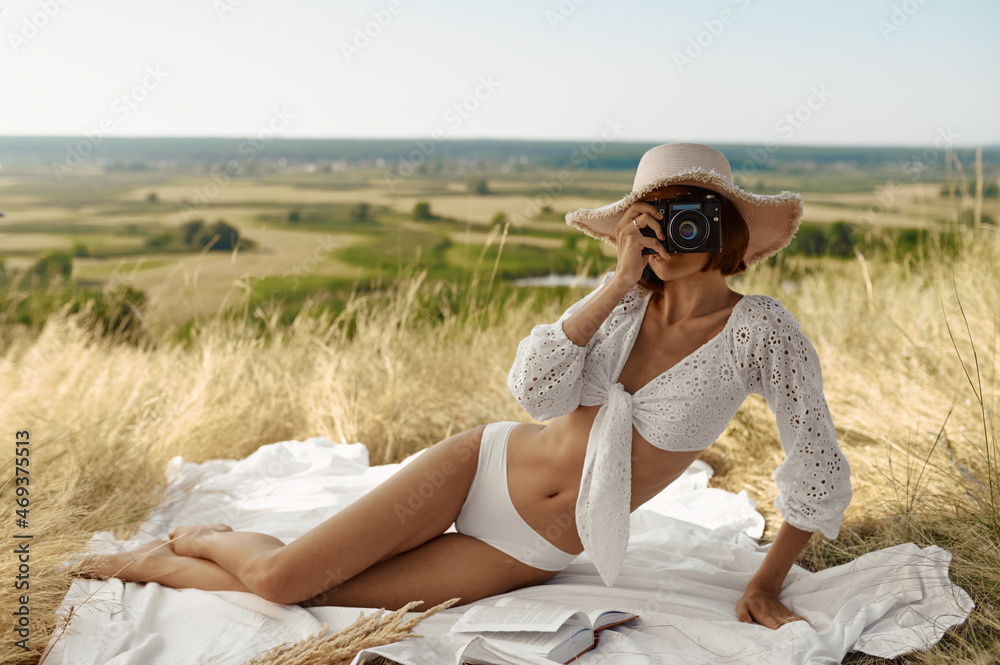 Sexy woman in hat lying on blanket in the field