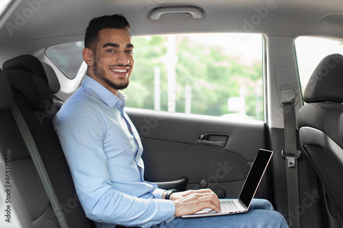 Handsome arabic entrepreneur sitting at auto, using laptop, mockup © Prostock-studio