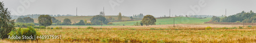 Autumn landscape panorama photography, the European part of the Earth. Druya, Belarus. Rural landscape with a rainy sky. Green field and village on the horizon