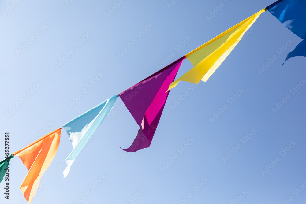 Garland of bright colored triangular flags developing in wind against background of blue sky. Celebration Party. Festive mood Garland of bright colored triangular flags developing in wind against background of blue sky. Celebration Party. Festive mood