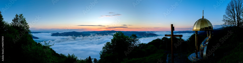 Panorama with a chapel on top of the mountain. Beautiful valley in the distance with white fog. Panorama with a chapel on top of the mountain. Beautiful valley in the distance with white fog.