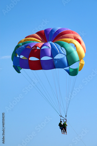 multicolored parachute with two people in the clear sky photo