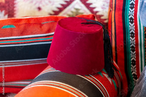 Fez or tarboosh with arabic or Ottoman style on Turkish Fabric Pattern. Oriental islamic middle eastern decor and Clothing, selective focus. Red turkish hat in classical oriental design home. colorful photo