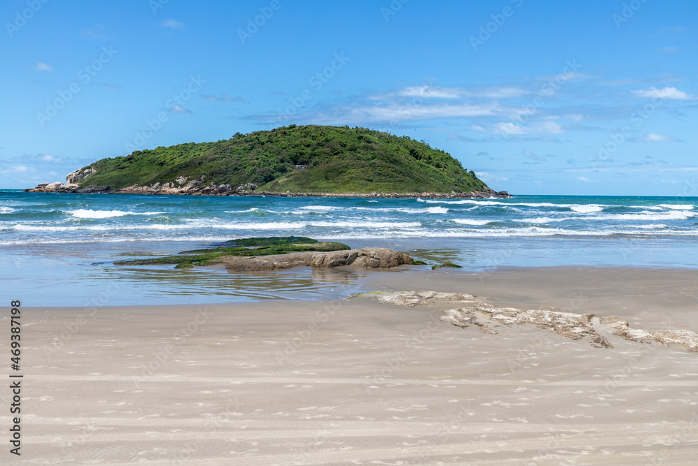 Beach view with sand, rocks, waves and island in background