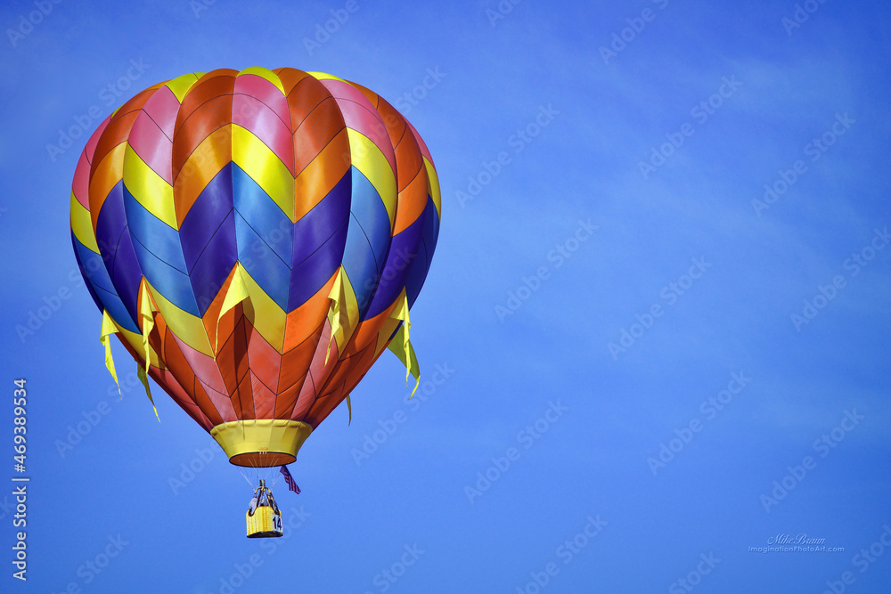 Fototapeta premium A brilliant hot air balloon soars through a clear blue sky.