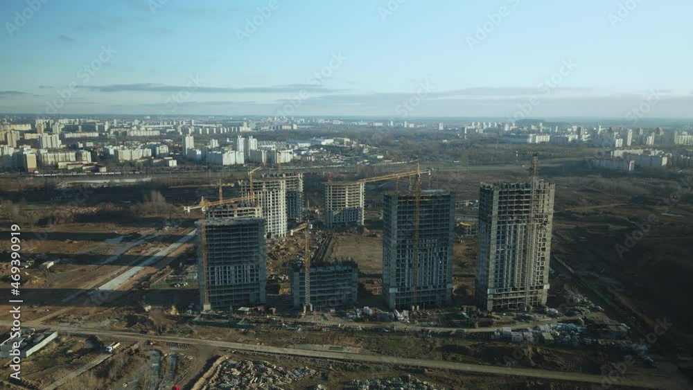 Construction site. Construction of modern multi-storey buildings. The work of construction cranes is visible. Against the background of the blue sky. Aerial photography. Construction site. Construction of modern multi-storey buildings. The work of construction cranes is visible. Against the background of the blue sky. Aerial photography.