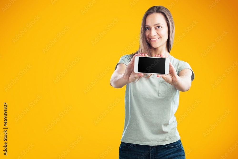 Excited and surprised young woman holding smartphone with blank screen in hand