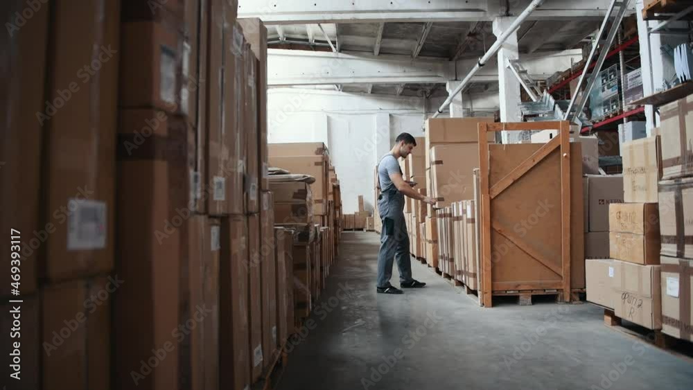 Young male worker in warehouse walks forward with pallet truck Young male worker in warehouse walks forward with pallet truck