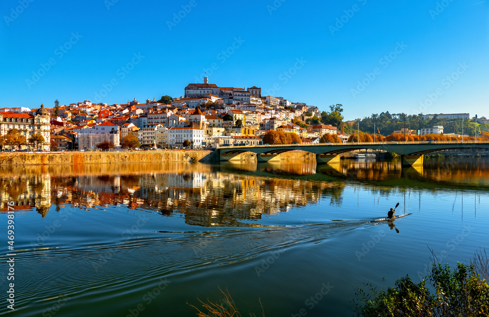 Canoísta a navegar em kayak no Rio Mondego e cidade de Coimbra com o reflexo na Água. Universidade de Coimbra e Ponte de Santa Clara.