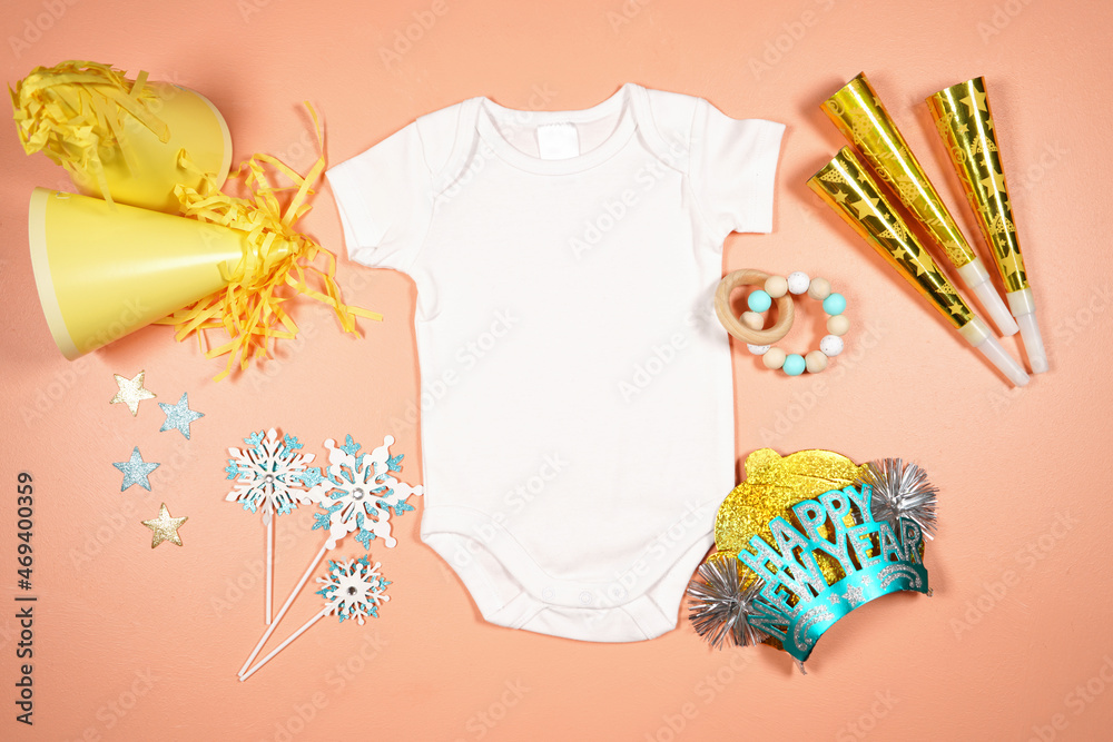 Naklejka premium Baby romper onesie bodysuit product mockup. New Year theme SVG craft product mockup styled with party hats and blowers decorations. Gold and blue theme creative composition flatlay.