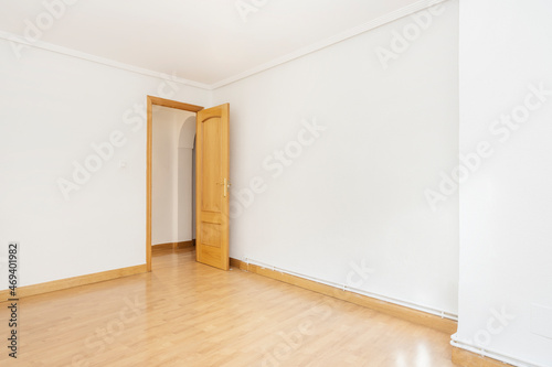 Empty room with light oak floors and carpentry with white painted walls