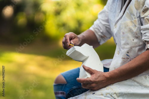 Cropped photo of a woman making the figure of a horse with polystyrene foam outdoors photo