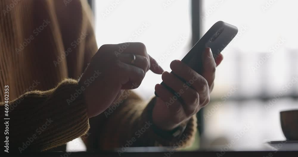 Close up shot of man hands with watch using mobile phone while working at laptop. Male fingers typing and tapping on smartphone. Texting and scrolling. Slow motion.