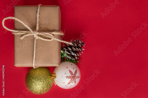 pink background with a gift box wrapped in paper with a cord bow next to Christmas balls to decorate  objects in studio  holiday