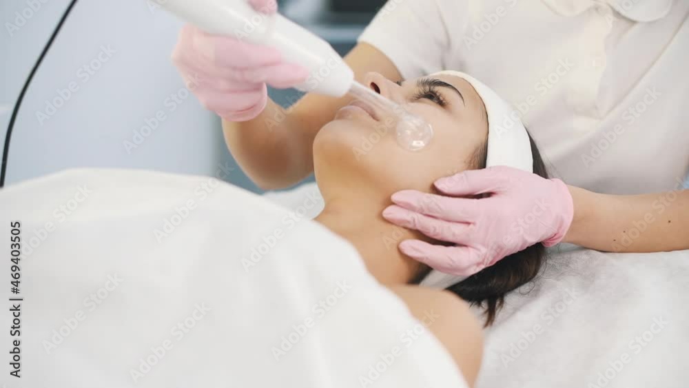 Close up view of woman that lying down in spa salon and have face cleaning procedure by using special modern device Close up view of woman that lying down in spa salon and have face cleaning procedure by using special modern device