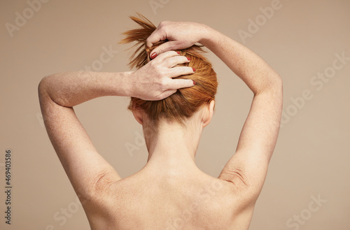 Minimal back view of young red haired woman with nude shoulders, copy space