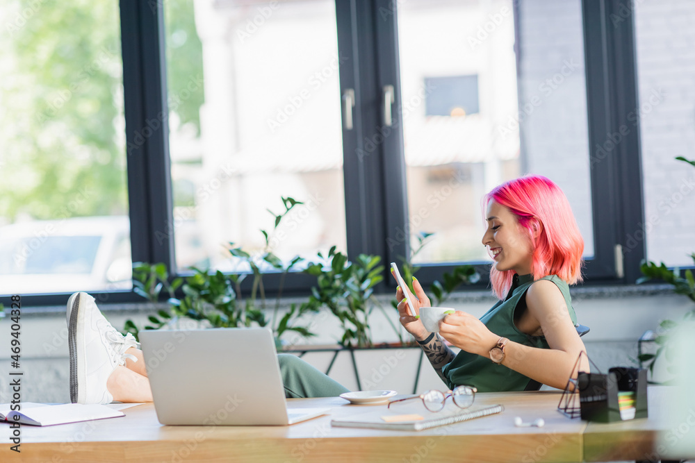 side view of happy businesswoman with pink hair holding smartphone and cup of coffee. side view of happy businesswoman with pink hair holding smartphone and cup of coffee.